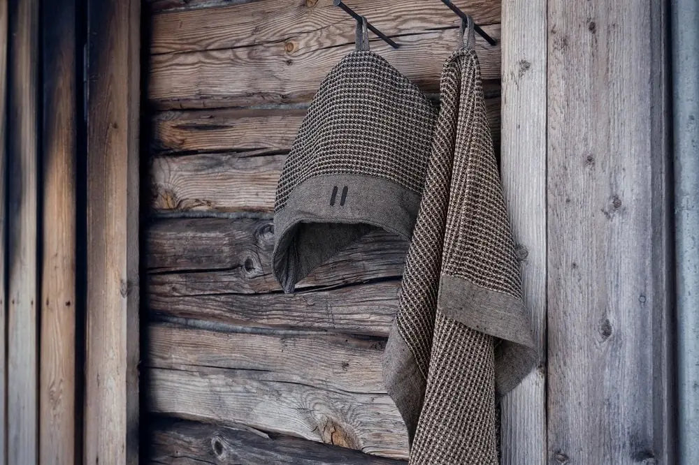 Premium wool felt sauna hats hanging on a rustic wooden sauna wall.